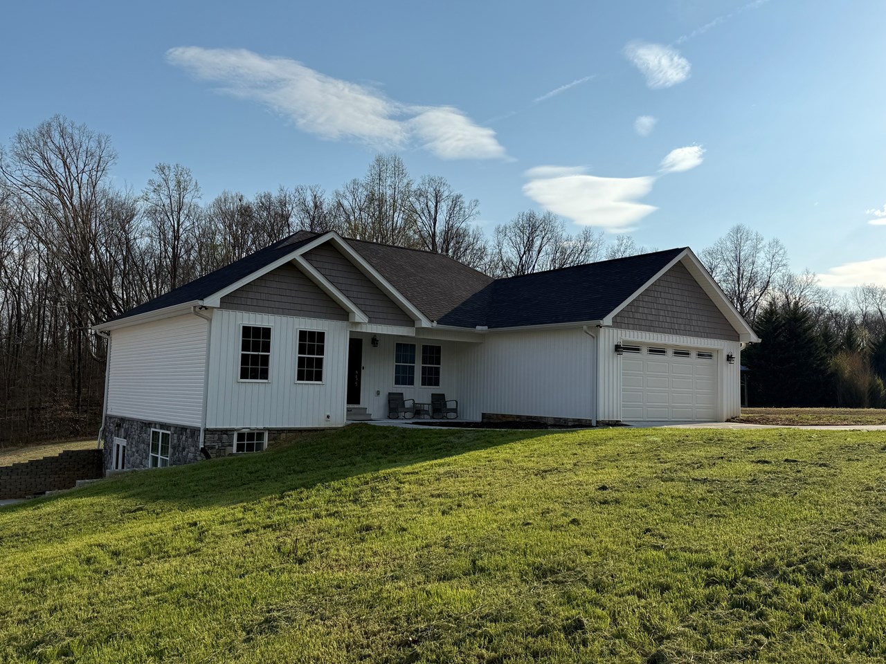 front/side side/front, stone siding, with white and grey, beautifully depicted with woods in the back drop