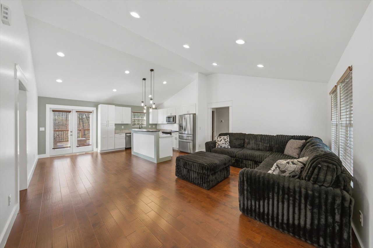 living room engineered hard wood cherry flooring, island, large sectional black couch.