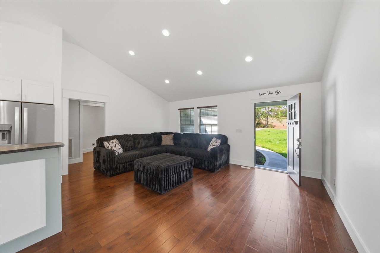 living room facing front door, recessed lighting vaulted ceiling, large windows